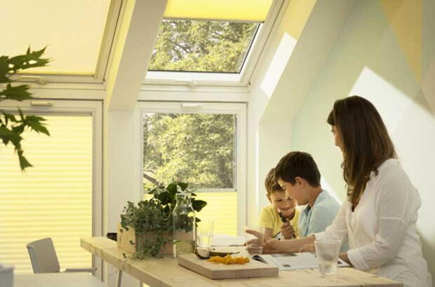Familie am Frühstückstisch unter der Dachschräge mit Dachfenstern | VELUX Magazin