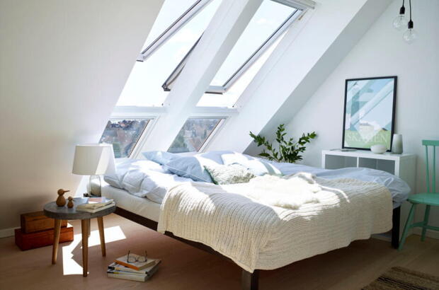 Ein Bett in einem hübsch eingerichteten Raum mit großen Fenstern: Im Schlafzimmer sollten Sie sich rundum wohl fühlen | VELUX Magazin