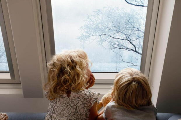 Kinder gucken durch ein Dachfenster auf Schnee | VELUX Magazin
