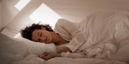 Eine Frau schläft entspannt in ihrem Bett unter der Dachschräge | VELUX Magazin