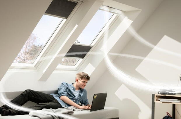 Junger Mann liegt auf dem Bett vor Dachfenstern | VELUX Magazin