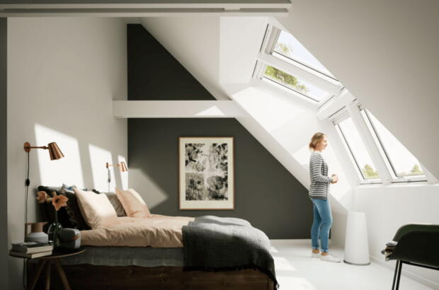 Frau steht im Schlafzimmer mit einer großen Velux Panorama Lichtlösung -  Velux Magazin