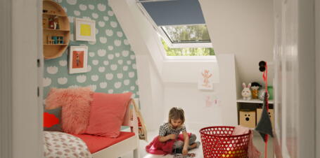 Mädchen sitzt in Kinderzimmer mit Dachfenster | VELUX Magazin