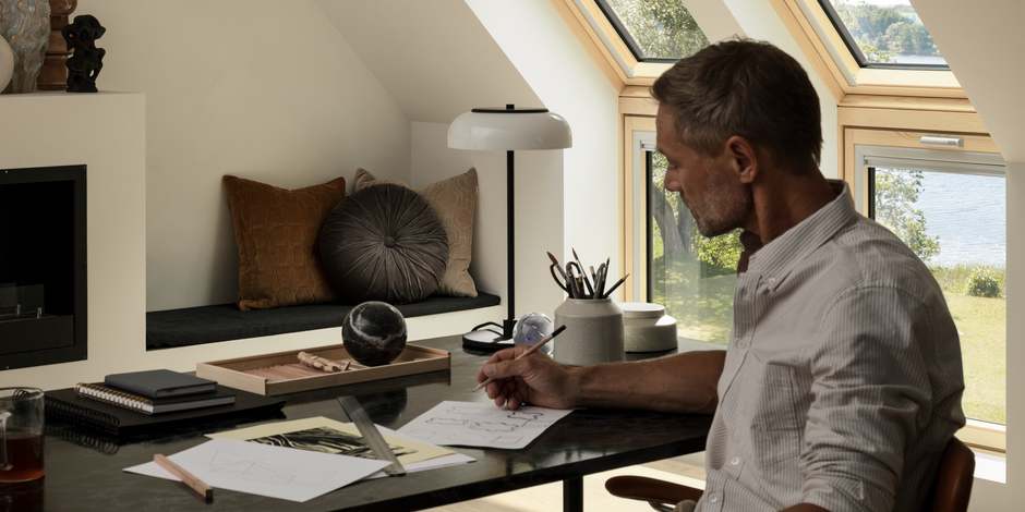 Mann arbeitet am Schreibtisch unter Dachschräge mit Lichteinfall | VELUX Magazin
