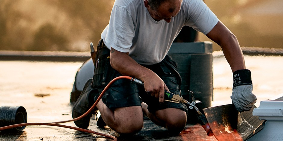 Mann verschweißt eine Bitumenbahn am Flachdach | VELUX Magazin